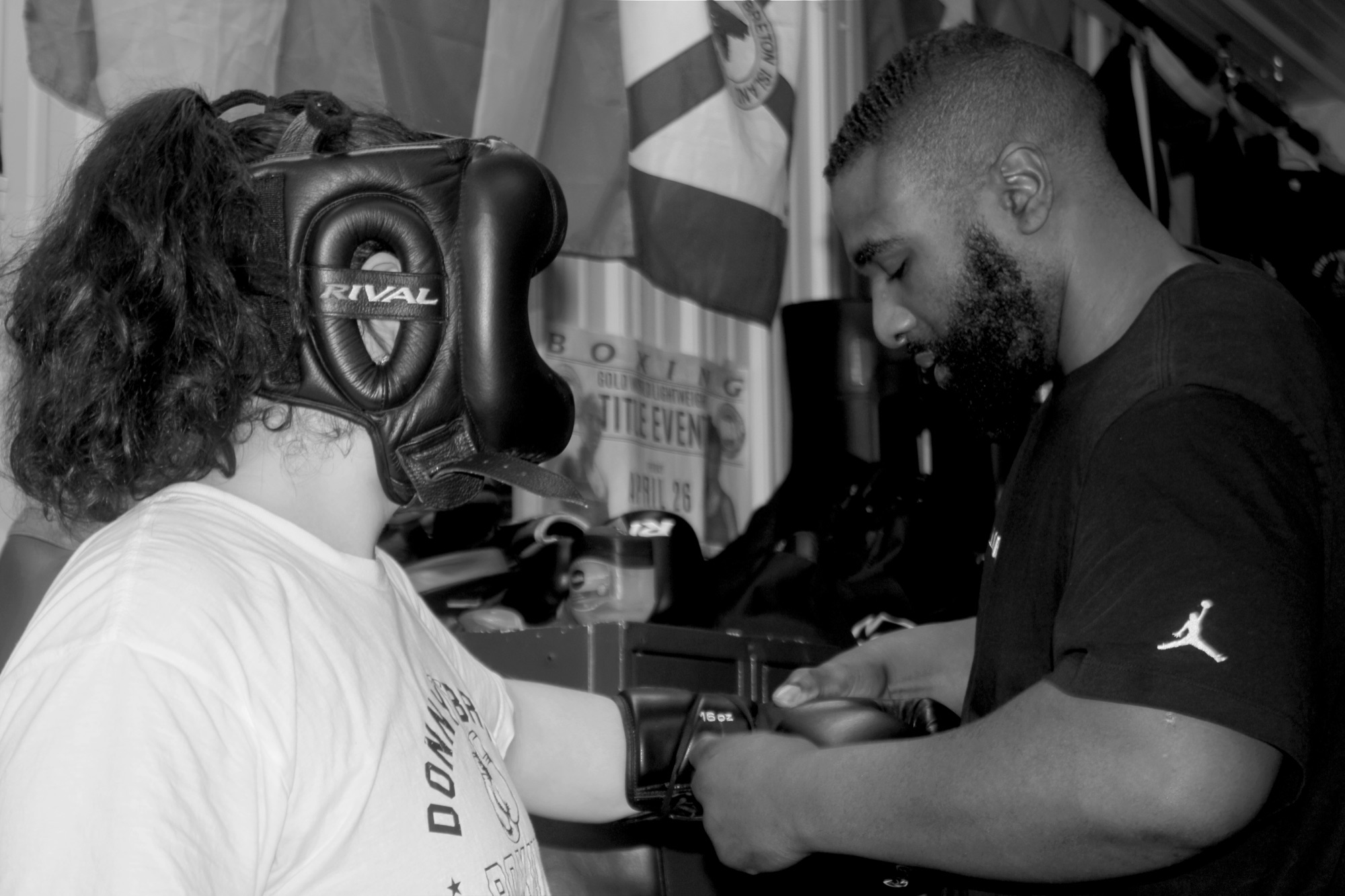 Un entraîneur du South West Boxing Club attache le gant d&rsquo;un boxeur, le boxeur portant un casque protecteur, les drapeaux du club au mur derrière eux